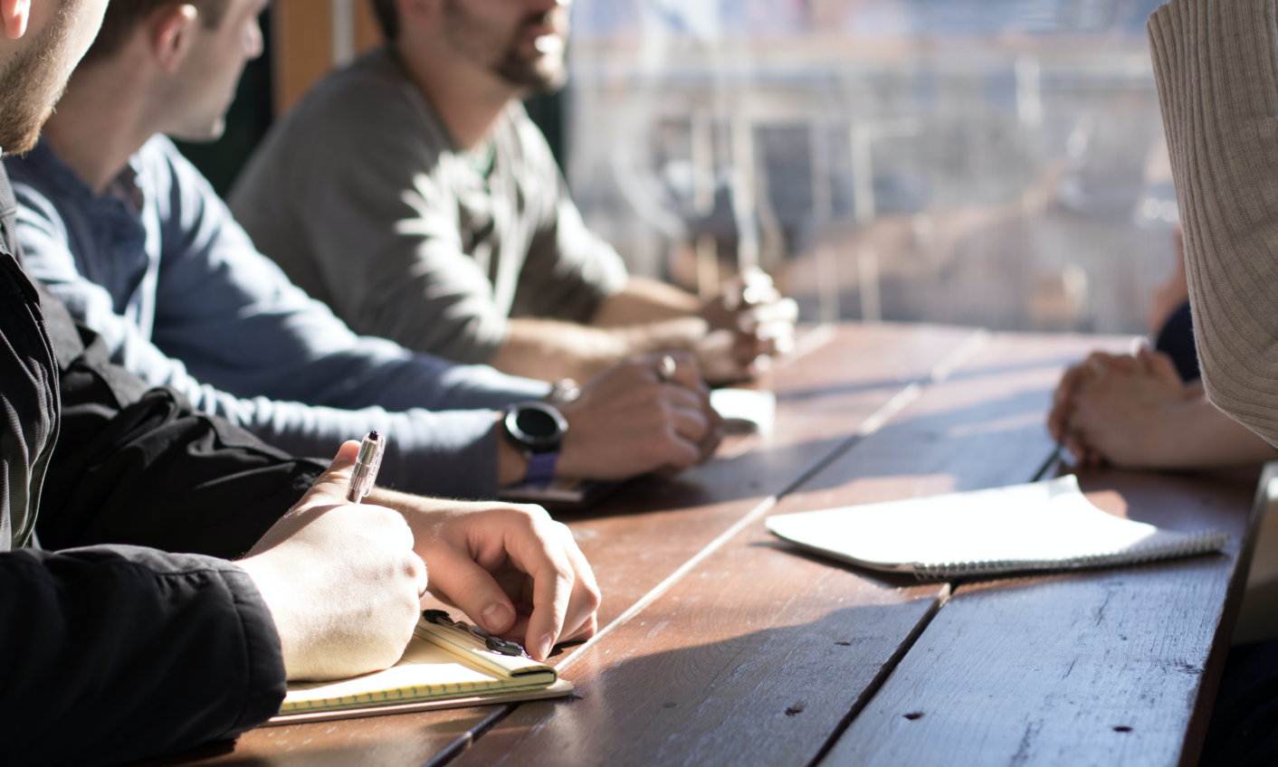 Group of 4 people having a meeting at a desk next to a high-rise window