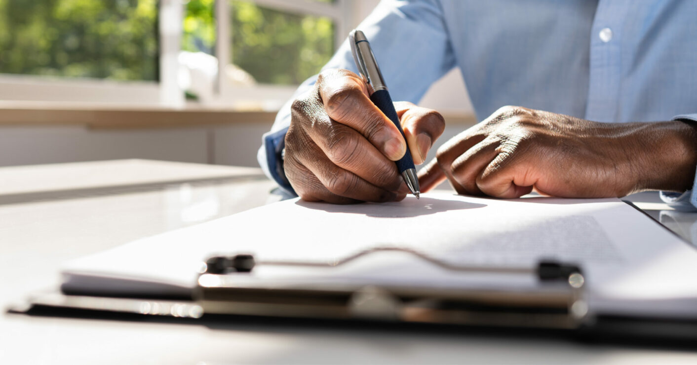 Man writing on some documents attached to a clipboard