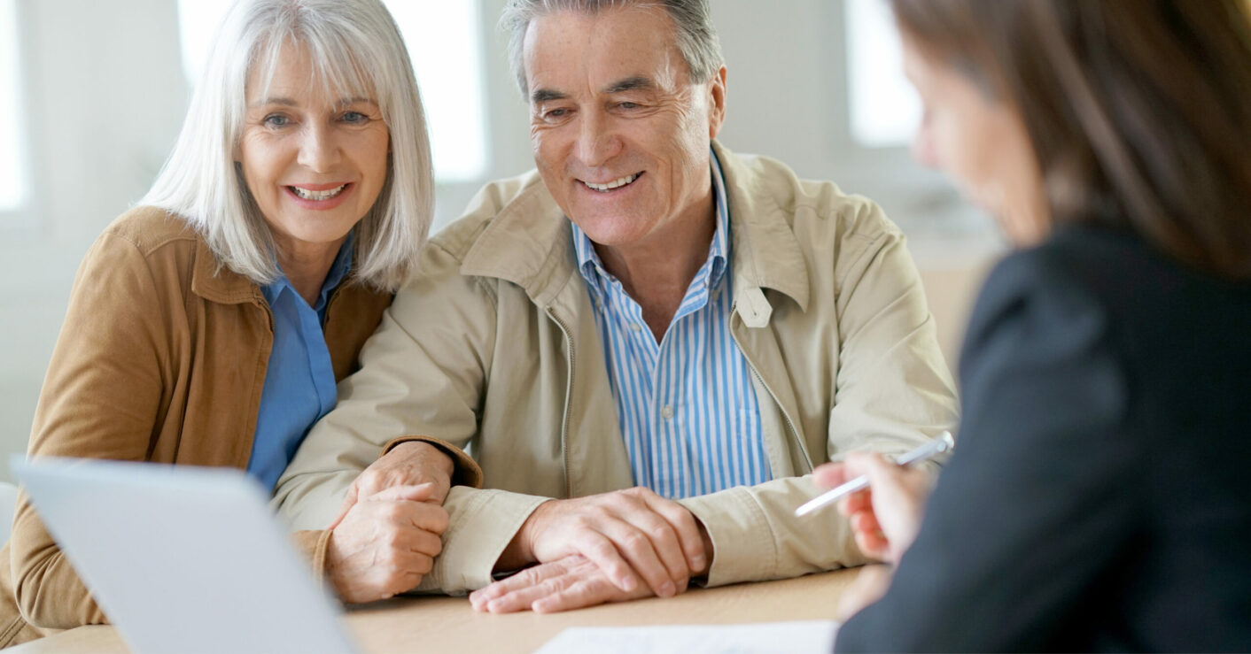 older couple meeting with an advisor, smiling and looking at a laptop