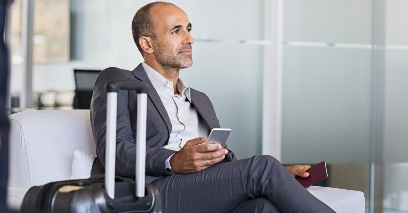 A business man works on his phone while waiting in an airport lounge