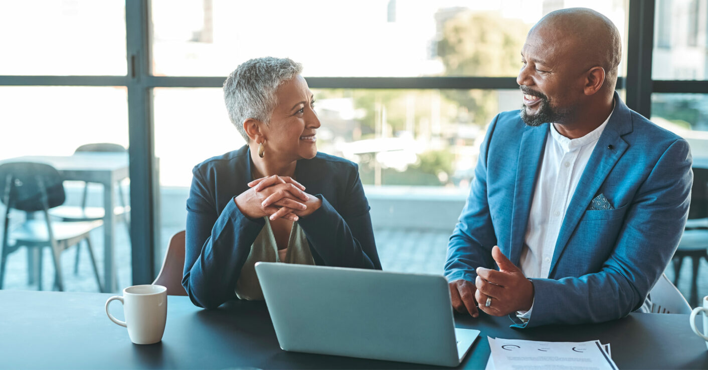 Two finance professionals discussing in front of a laptop