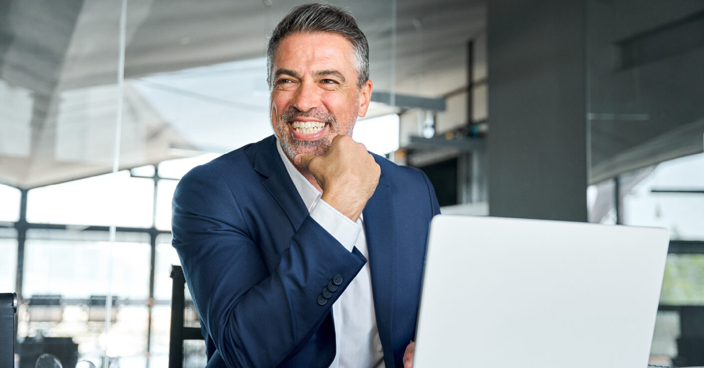 businessman joyfully smiling at his laptop